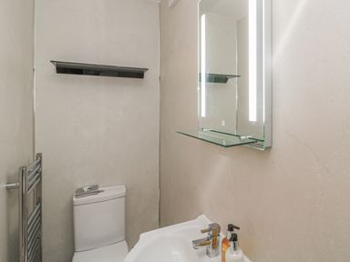 A bathroom with a toilet sink mirror with lights and a towel rail at Vallum Kiosk in Haltwhistle