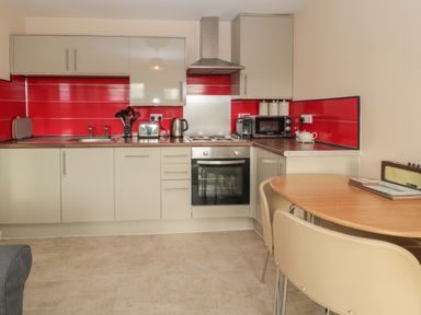 A kitchen with beige cabinets red backsplash and wooden table with chairs at Vallum Kiosk in Haltwhistle