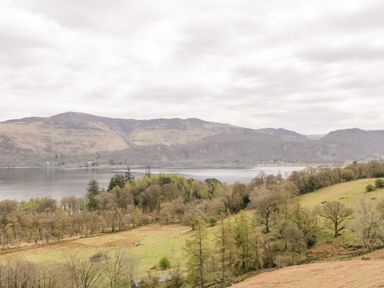 A landscape with a lake in the middle surrounded by hills and trees at Holly Cottage in Keswick