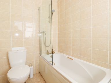 A bathroom with a toilet and a bathtub with a shower at Holly Cottage in Keswick