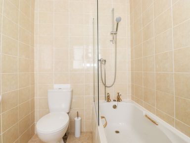 A bathroom with a toilet bathtub shower fixtures and tiled walls at Holly Cottage in Keswick
