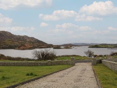 A gravel driveway leading to a lake with hills and small islands in the background at Ranny Roe in Portsalon County Donegal