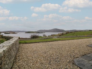 A gravel driveway with stone walls overlooking a body of water and hills in the distance at Ranny Roe in Portsalon County Donegal