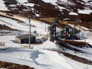 A ski lift station with skiers and snow on a mountain slope at Otter Lodge in Feshiebridge near Aviemore