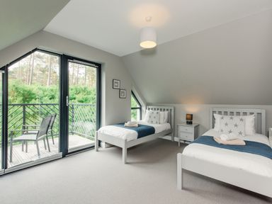 A bedroom with two single beds a nightstand and glass doors leading to a balcony at Otter Lodge in Feshiebridge near Aviemore