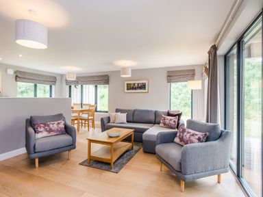 A living room with two armchairs a sofa and a wooden coffee table at Otter Lodge in Feshiebridge near Aviemore