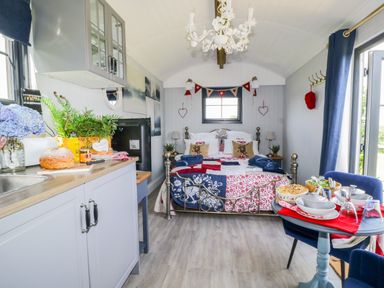 A small room with a bed at the back kitchen cabinets on the left and a dining table with chairs on the right at High Rigg Shepherd's Retreat in Brampton Cumbria