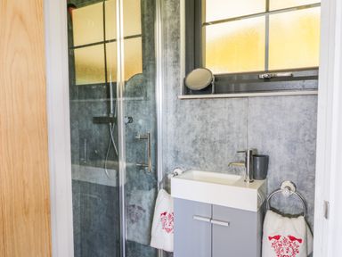 A bathroom with a shower cubicle sink with faucet mirror and towels at High Rigg Shepherd's Retreat in Brampton Cumbria