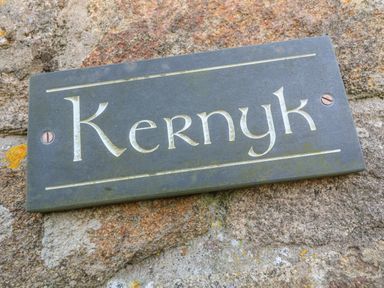 A metal sign with the word Kernyk on a stone wall at Kernyk Rinsey near Porthleven
