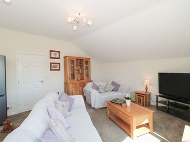 A living room with two sofas a wooden coffee table a television on a stand and a wooden cabinet at The Cider Shed in Winscombe
