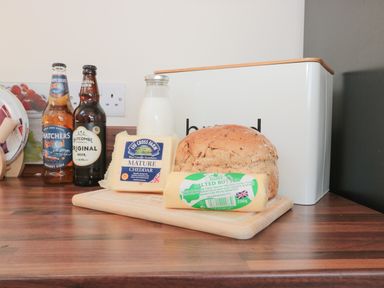 A kitchen countertop with a bread box milk bottle bread cheese butter and two bottles of drinks at The Cider Shed in Winscombe