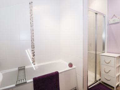 A bathroom with a bathtub a shower cubicle and a white storage unit at The Cider Shed in Winscombe