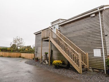 The exterior of a wooden building with an outdoor staircase and plants at The Cider Shed in Winscombe