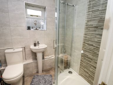 A bathroom with a toilet sink shower and tiled walls at Maplebeck in Whitby