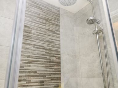 A shower area with a rain shower head and tiled walls in varying shades of gray at Maplebeck Whitby