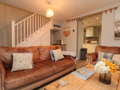 A living room with brown leather sofas cushions wooden coffee table and staircase at Maplebeck in Whitby
