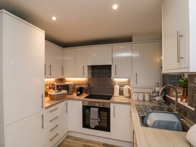 A kitchen with white cabinets a built in oven a sink a microwave and kitchen utensils at Maplebeck in Whitby