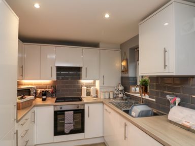 A kitchen with white cabinets a stove a sink and countertop appliances at Maplebeck in Whitby