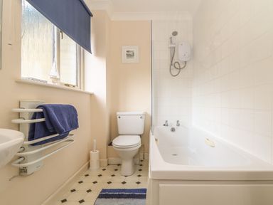 A bathroom with a bathtub shower toilet towel rack and window at Deja Blue in Falmouth