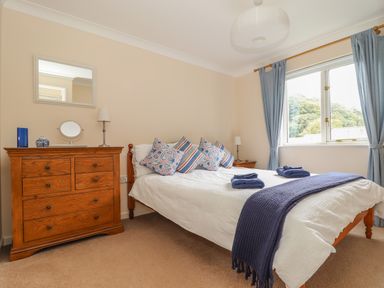 A bedroom with a bed with pillows and folded towels beside a wooden dresser with a mirror at Deja Blue in Falmouth
