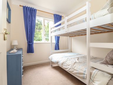 A bedroom with white bunk beds blue chest of drawers and blue curtains at Deja Blue in Falmouth