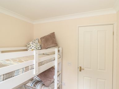 A small bedroom with a white bunk bed and pillows next to a closed door at Deja Blue in Falmouth