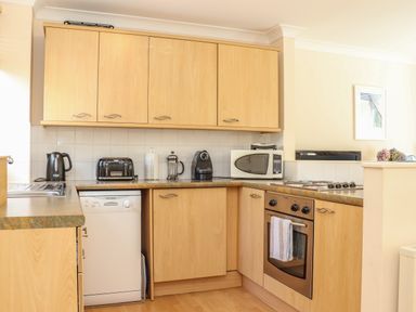 A kitchen with wooden cabinets a dishwasher microwave toaster coffee maker and oven at Deja Blue in Falmouth