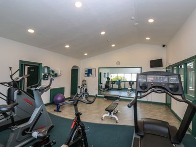 A gym room with exercise bikes a treadmill a bench and weights at Deja Blue in Falmouth