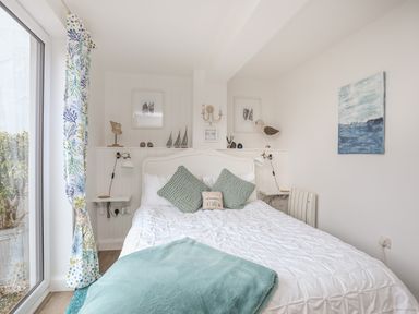 A bedroom with a bed with pillows a blanket wall art and curtains at The Old Boat Store in Morfa Nefyn