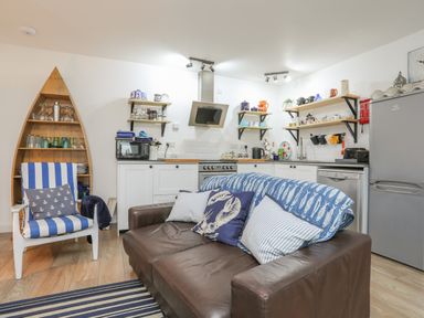 A kitchen and seating area with a brown leather sofa and striped armchair at The Old Boat Store in Morfa Nefyn