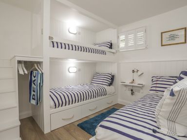 A bedroom with bunk beds and a single bed with striped bedding at The Old Boat Store in Morfa Nefyn