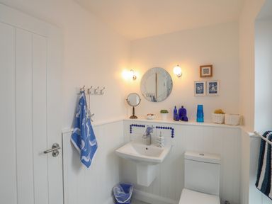 A bathroom with a sink toilet blue towel and blue decorative items at The Old Boat Store in Morfa Nefyn