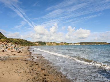 A sandy beach with small pebbles next to the sea under a blue sky at The Old Boat Store in Morfa Nefyn