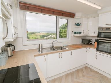 A kitchen with white cabinets wooden countertops a window showing a countryside view at Little Valley View in Angarrack