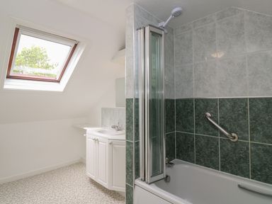 A bathroom with a bathtub shower combination and a sink under a skylight window at Little Valley View in Angarrack
