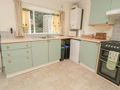 A kitchen with green cabinets a double sink a dishwasher and a stove at Wordsworth Cottage West in Longframlington