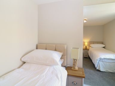 A room with two single beds separated by a wall with bedside tables and lamps at Rosebank Cottage in Mortehoe