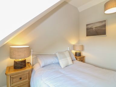 A bedroom with a double bed two bedside tables with lamps and a framed picture on the wall at Rosebank Cottage in Mortehoe