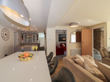 A kitchen island with fruit bowl and drinks with dining area and living room visible at Rosebank Cottage in Mortehoe