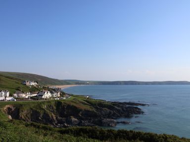 A coastal village with houses on cliffs overlooking the sea and a sandy beach at Rosebank Cottage in Mortehoe