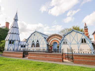 A house with a tall pointed turret and blue timber framing surrounded by a brick and iron fence at Hunters Moon in Tenbury Wells