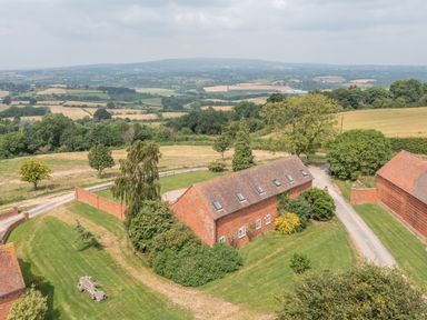 A rural landscape with brick buildings surrounded by grass and trees at Hunters Moon in Tenbury Wells