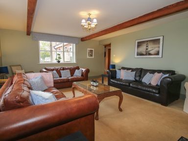 A living room with two brown leather sofas one black leather sofa a wooden coffee table and framed pictures on the wall at Hunters Moon in Tenbury Wells
