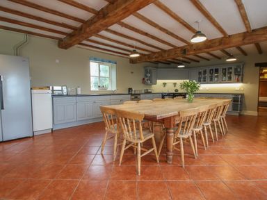 A kitchen with wooden dining table and chairs under exposed wooden beams at Hunters Moon in Tenbury Wells