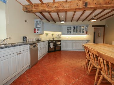 A kitchen with cabinets appliances and a wooden dining table with chairs at Hunters Moon in Tenbury Wells
