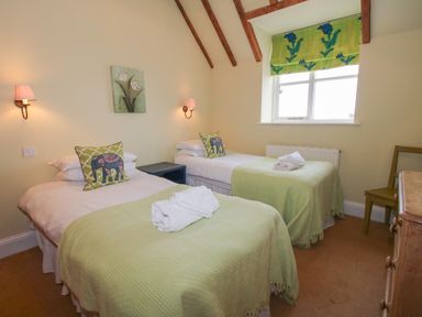 A bedroom with two single beds with green blankets and elephant pillows at Hunters Moon Tenbury Wells