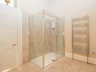 A bathroom with a glass shower enclosure and a chrome towel radiator at Hilltop House in Tenbury Wells