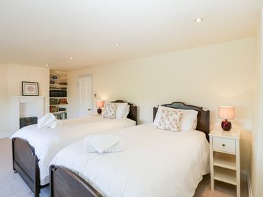 A bedroom with two single beds a nightstand and a fireplace at Hilltop House in Tenbury Wells