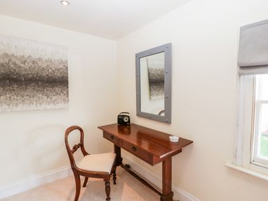 A small room with a wooden desk and chair a mirror on the wall and a window at Hilltop House in Tenbury Wells