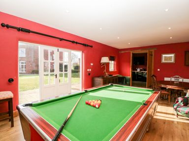 A games room with a pool table, dining table, chairs, and large windows at Hilltop House in Tenbury Wells